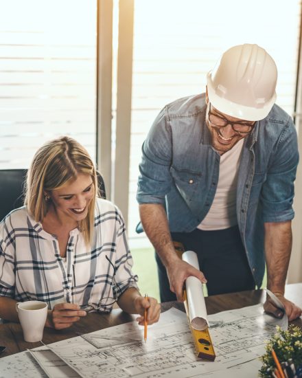 Two young pensive architect colleagues are working on a new project, analyzing blueprints and talking about it in the office.